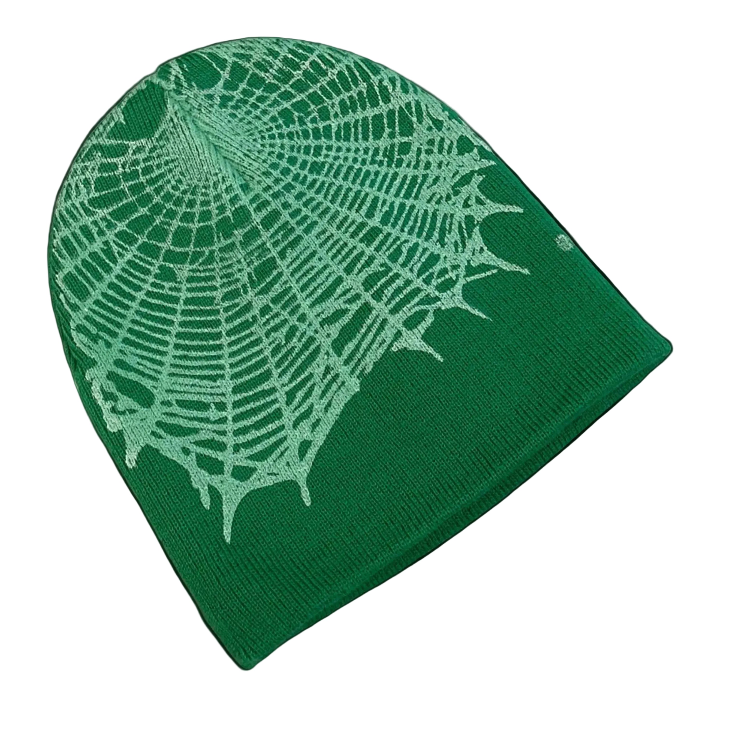 Green fabric beanie with white spider web pattern on a white surface