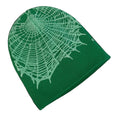 Green fabric beanie with white spider web pattern on a white surface