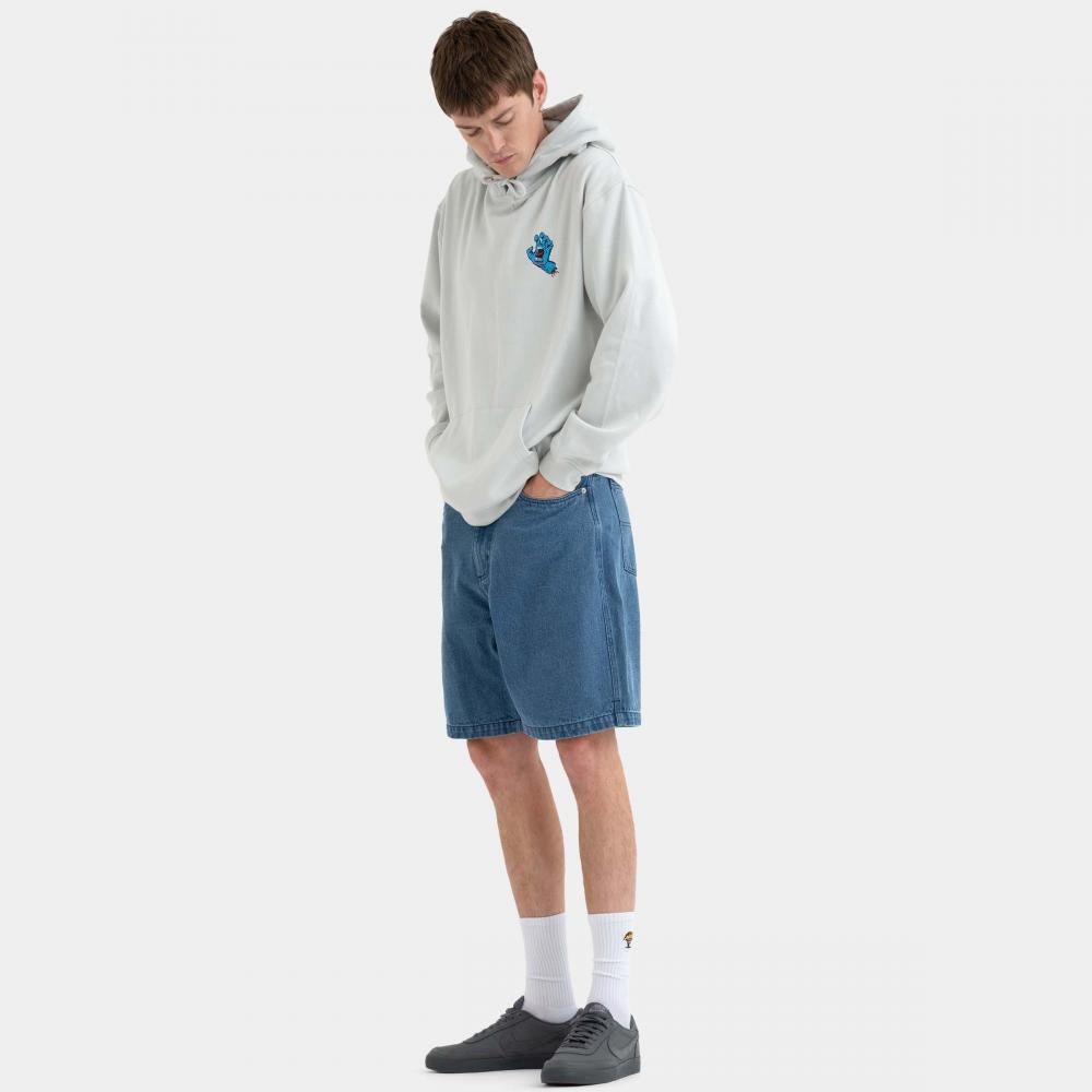 A young man wearing a light gray hoodie with a blue graphic on the chest, blue denim shorts, white socks, and dark gray shoes, standing against a solid off-white background.