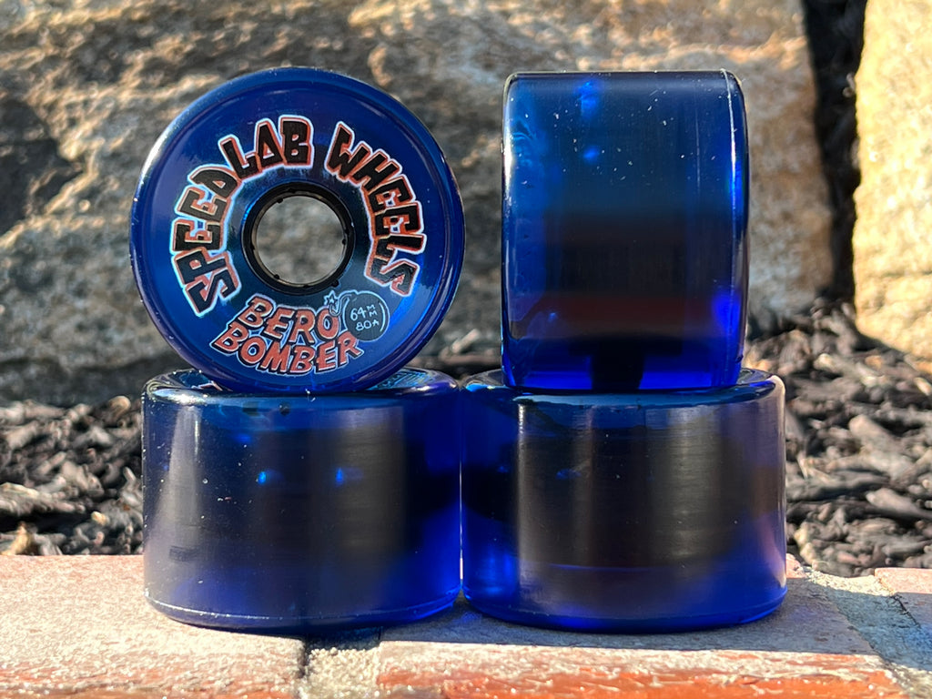 Blue skateboard wheels with visible branding on a stone surface